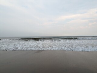 A serene evening at Rushikonda Beach, in Andhra Pradesh, India, with soft golden hues from the setting sun reflecting on the calm, blue waters.