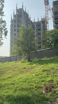 Construction site with a crane. Multiple story building with grey structure and crane. Apartments under construction with a crane.