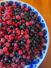 blueberries and raspberries in a big bowl after a forest walk in the summer