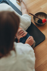 A man lying on a mat with a blindfold, practicing breathing exercises while a woman acts as a...