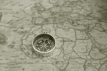 Classic round compass on background of old vintage map of world