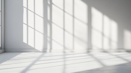 Sunlight casts geometric shadows through large windows onto a pristine white floor, creating a mesmerizing interplay of light and shadow in a minimalist interior space.