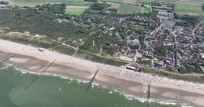 Drone view of a seaside town with a sandy beach and green spaces on a sunny day in Domburg, Zeeland