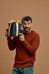 Surprised man holding black gift boxes with golden ribbon and looking at camera.