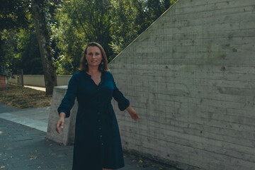 Smiling caucasian middle-aged mature woman looking at the camera walking in the park.