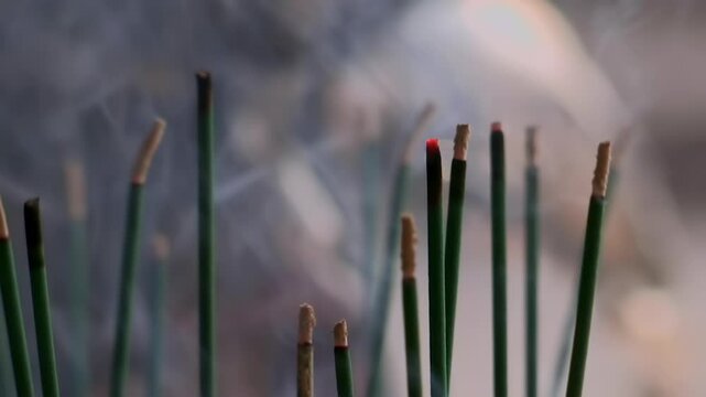 Multiple incense sticks burning with smoke gently rising, creating a calming and peaceful atmosphere, close-up of incense sticks in a meditative environment with soft focus