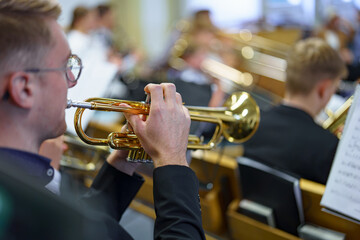 A musician in an orchestra plays a musical composition on a trumpet in an orchestra.