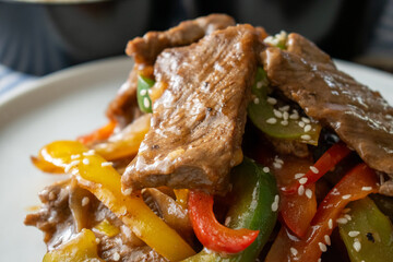 Stir-Fried Beef with Colorful Bell Peppers and Sesame Seeds on White Plate, Asian Cuisine Close-up