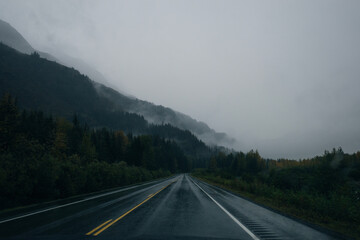 Scenic Route, Alaska Hwy, during a sunny and cloudy day. Mountains in Background.