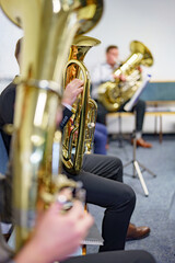 A male musician holds a trumpet in a brass band.