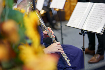 Fototapeta premium A girl musician plays a musical composition on the flute in an orchestra.