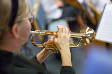 A girl musician plays the trumpet in a folk wind instruments orchestra.