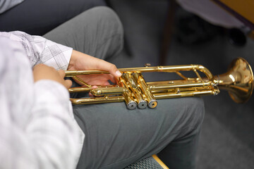 A male musician holds a trumpet in a brass band.