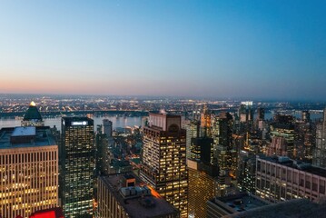 A city skyline at dusk with the lights of the buildings reflecting on the water