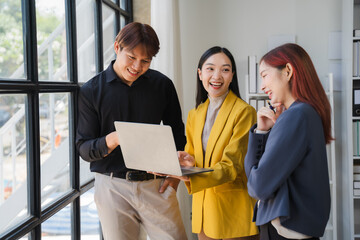 Collaborative Brainstorming:  A diverse team of business professionals collaborate on a laptop in a modern office setting.