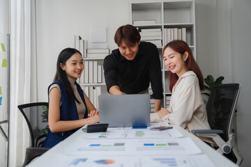 Collaborative Brainstorming: A diverse team of professionals engages in a dynamic brainstorming session, leaning over a laptop and analyzing data, showcasing teamwork, innovation.