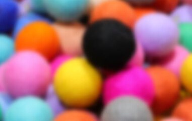 intentionally blurred background of colorful felted wool balls perfect for the concept of pastime