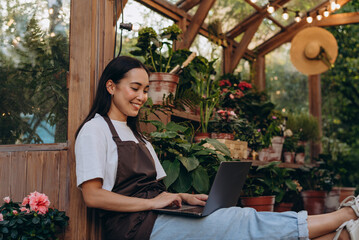 Young woman working by portable device and communicating with distant consumers of shop