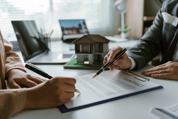 Real estate agent holding pen and pointing on document for house purchase contract, woman signing a contract to buy house