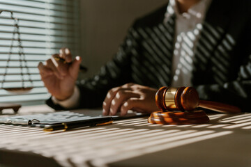 Lawyer reviewing a contract and holding a pen, with a gavel on the table in his office