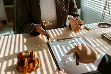 Lawyers reviewing and negotiating the terms of a contract during a meeting, ensuring clarity and...