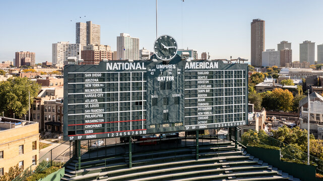 Chicago, IL, USA - October 9, 2024: Drone view of the MLB National and American League scoreboard inside of Wrigley Field with skyscrapers and Lake Michigan in the background.
