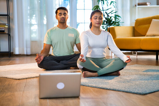 Indian Asian couple practicing pranayam and breathing exercises together, online yoga class at home