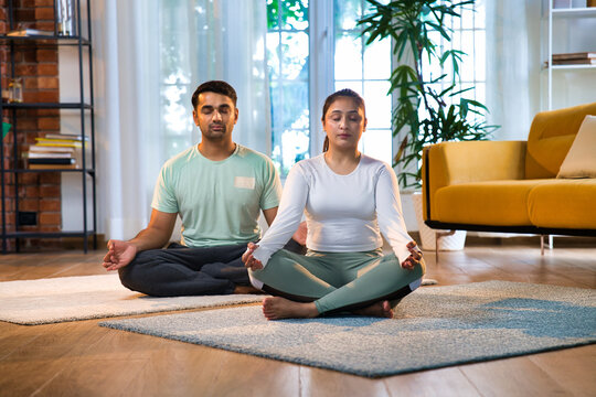 Indian Asian couple practicing pranayam and breathing exercises together, online yoga class at home