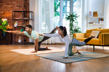 Young Indian Asian couple practicing Parsva Balasana, enjoying a mindful yoga session at home