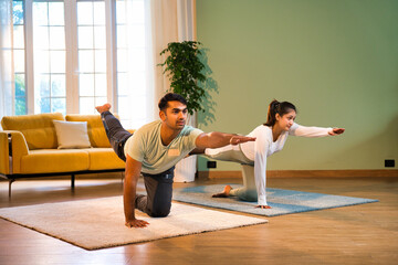 Young Indian Asian couple practicing Parsva Balasana, enjoying a mindful yoga session at home