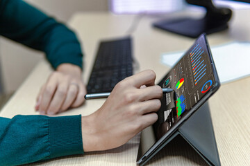 Side view of a business man using a tablet in the office with a pen, analyzing some digital graphics , online work concept