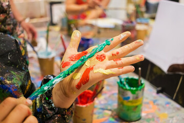 Children enjoy painting in art class, with dirty hands and smocks full of paint.