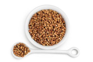 Raw buckwheat in ceramic bowl isolated on white background. Top view. Flat lay