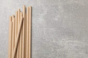 Bamboo drinking straws on gray textured table, top view. Space for text
