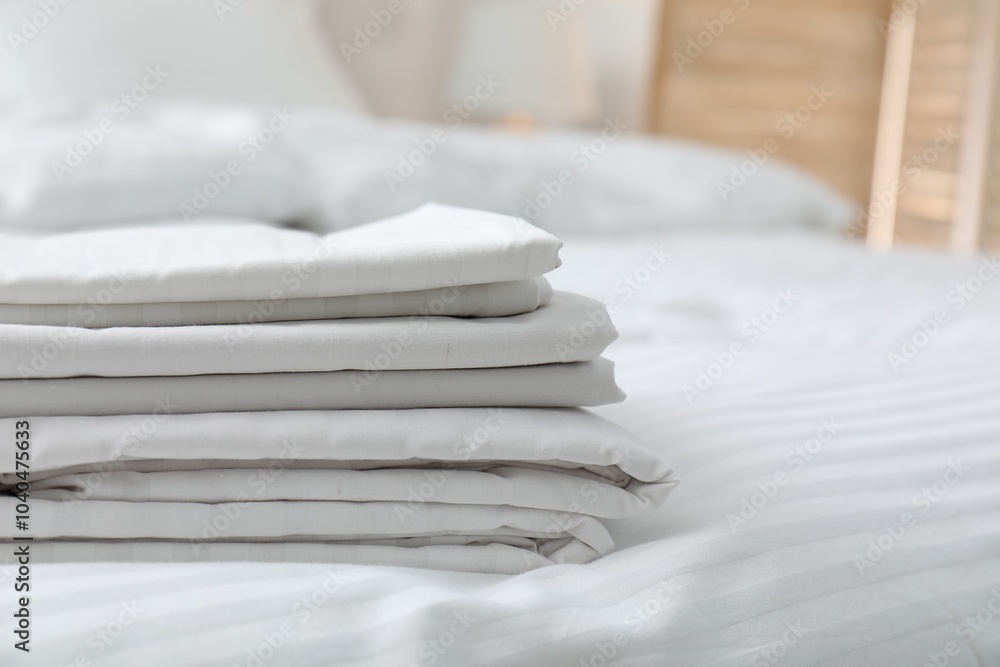 Poster Stack of clean linens on bed indoors, closeup