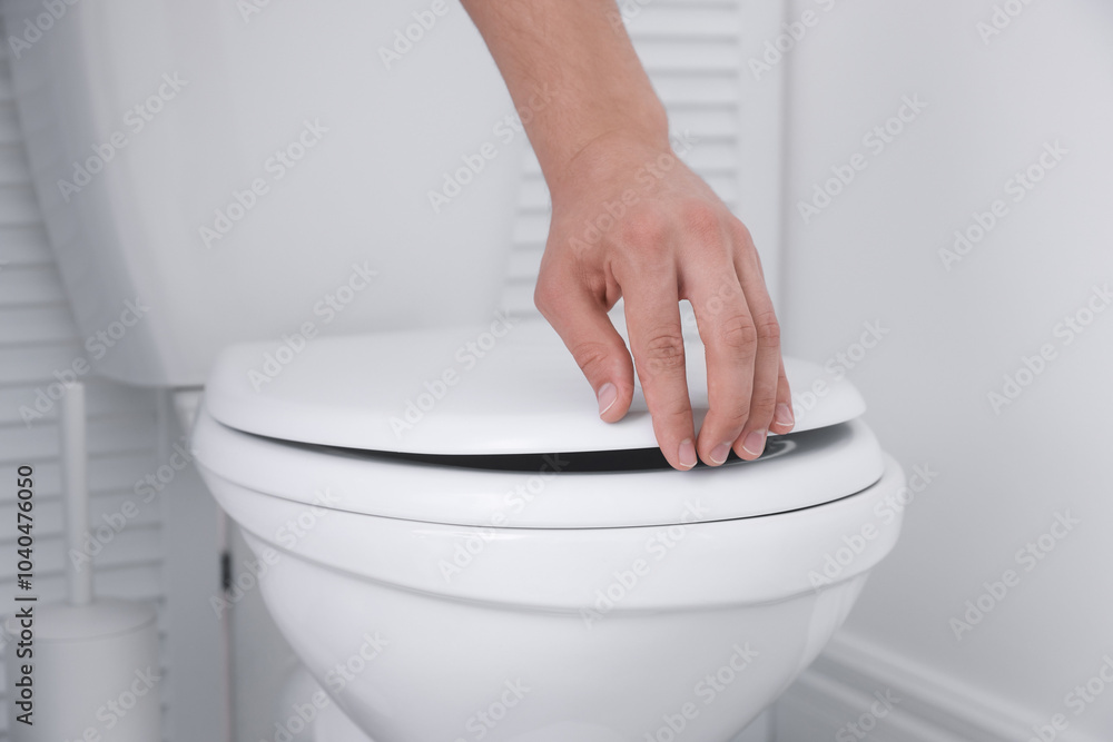 Wall mural Man closing toilet seat in bathroom, closeup