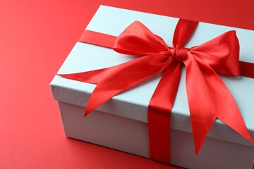 Gift box with bow on red background, closeup
