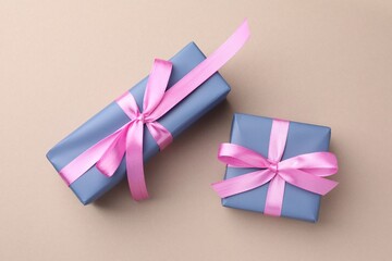 Gift boxes with pink bows on beige background, top view