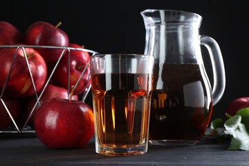 Tasty fresh apple juice and fruits on black wooden table