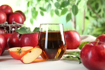 Fresh apple juice in glass and fruits on white table outdoors