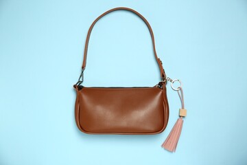 Bag with pink leather keychain on light blue background, top view