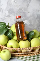 Tasty apple juice in glass bottle, green leaves and fresh fruits on table