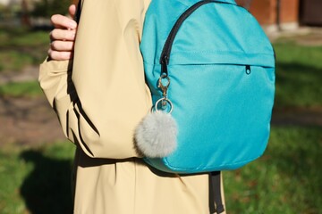 Woman with faux fur keychain on her backpack outdoors, closeup