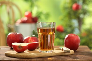 Tasty apple juice in glass and fresh fruits on wooden table outdoors