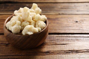 Frozen cauliflower in bowl on wooden table, closeup. Space for text