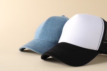 Stylish baseball caps on beige background, closeup. Mockup for design