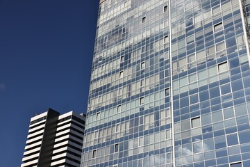 Obraz premium Exterior of modern building with many windows against blue sky, low angle view