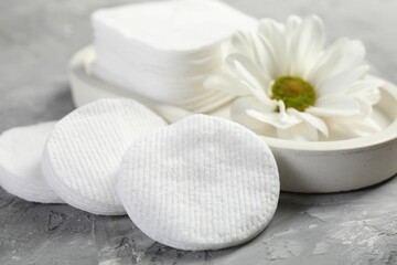 Clean cotton pads and flower on grey table, closeup