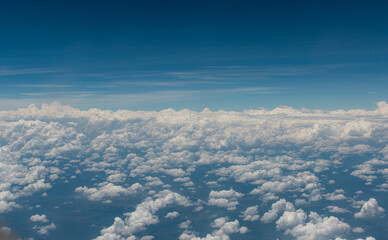 Paisaje de cielo con nubes arreboladas se extiende bajo un cielo azul profundo, visto desde un avión