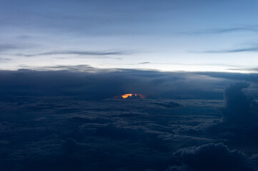 Un intenso atardecer con el sol escondido entre las nubes, ilumina con intensos tonos rojizos y anaranjados, creando una escena que evoca la imagen de un volcán en erupción